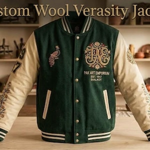 May include: A dark green wool varsity jacket with cream-colored sleeves, featuring a front button closure, striped ribbed cuffs, and collar. Embroidered details include a peacock, floral patterns, and the text Pak Art Emporium Est. 1947 Sialkot.