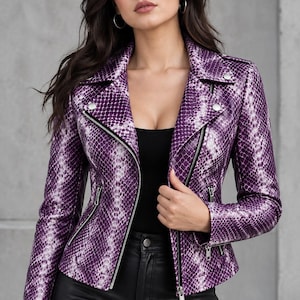 Puede incluir: Una chaqueta de motorista con estampado de piel de serpiente en color morado y blanco, con solapas, herrajes metálicos plateados, cierre de cremallera frontal asimétrico y dos bolsillos laterales con cremallera. Tiene mangas largas.
