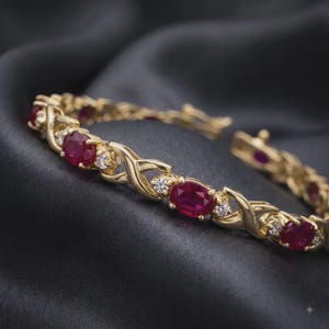 Könnte beinhalten: Ein goldfarbenes Gliederarmband mit abwechselnd oval geschliffenen, tiefroten Rubinen und kleinen, runden, klaren weißen Steinen. Die Metallglieder sind in einem sich wiederholenden Kreuzmuster gestaltet, das jede Steinfassung verbindet.