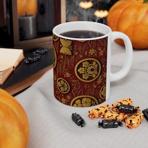 May include: A white ceramic mug featuring a deep red background with a repeating pattern of gold circular floral emblems and small gold butterflies. The mug has a smooth handle and is filled with a dark liquid, showcasing a detailed, ornate design.