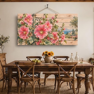 Könnte beinhalten: Ein rechteckiges Wandbild, gedruckt auf horizontalen Holzplanken, mit einer lebendigen Illustration von großen rosa Stockrosen im Vordergrund und einer Küstenlandschaft mit blauem Meer im fernen Hintergrund.