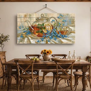 Op de afbeelding: Een rechthoekige wanddecoratie met een schilderij van een glazen theepot gevuld met thee, schijfjes citroen en muntblaadjes, omringd door kleine blauwe bloemen. Het kunstwerk is gedrukt op horizontale houten planken en hangt aan een zwart koord.