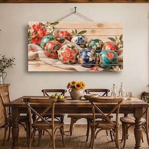 Könnte beinhalten: Ein rechteckiges Wandbild mit einer horizontalen Anordnung runder, handbemalter Keramikornamente, die mit leuchtenden Blumenmustern in Rot-, Blau- und Grüntönen verziert sind und auf einem hellen, über Holzplanken drapierten Stoff liegen.