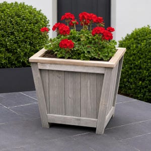 Puede incluir: Una maceta cuadrada de madera con un acabado gris desgastado y un borde de madera clara natural. La maceta está llena de un racimo vibrante de flores de geranio rojo brillante con hojas verdes festoneadas que sobresalen por los bordes.