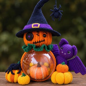 Peut inclure: Une figurine citrouille au crochet portant un chapeau de sorcière bleu foncé avec une bande violette et une araignée suspendue, avec un œil en bouton et une bouche cousue. Une sphère transparente contient une petite citrouille et une chauve-souris.