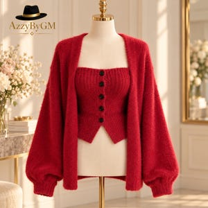 May include: A bright red two-piece set consisting of a fuzzy knit cardigan with long, loose sleeves and a matching strapless knit top featuring a vertical ribbed texture and a front row of five small black buttons on a mannequin.
