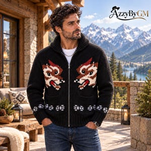 May include: A black knit zip-up sweater featuring a shawl collar and a graphic pattern of two stylized wolf heads in brown, red, and white on the chest. The garment includes ribbed cuffs and hem, two front pockets, and a silver-tone metal zipper.