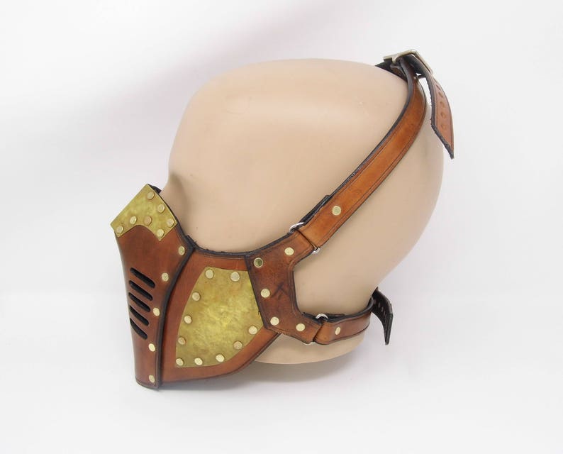 May include: A brown leather steampunk-style mask with brass accents and a strap that goes over the head.