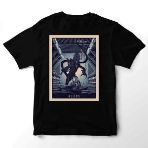 Op de afbeelding: Een zwart t-shirt met een rechthoekige grafische print van een donker, biomechanisch wezen in het water achter een persoon. De scène speelt zich af in een metalen gang met het woord ALIENS in witte hoofdletters aan de onderkant.