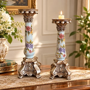 May include: Two ornate candle holders with a light blue crackle finish, featuring painted floral patterns in red, purple, and green. The bases and tops are finished in a metallic silver with intricate scrollwork and decorative moulding details.