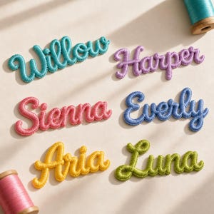 Peut inclure: Six écussons brodés avec des noms en écriture cursive : Willow en bleu sarcelle, Harper en violet, Sienna en rose, Everly en bleu, Aria en jaune et Luna en vert, accompagnés de deux bobines de fil de couleur bleu sarcelle et rose.