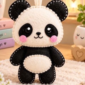 May include: A felt panda ornament featuring a cream-coloured face and belly with black ears, limbs, and eye patches. The panda has shiny black eyes, a small black nose, a stitched mouth, and round pink cheeks, all joined with visible white stitching.