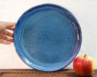 以下が含まれることがあります： 斑点のある釉薬が施された青いセラミックプレート。プレートは茶色の織り方のプレースマットの上に置かれています。