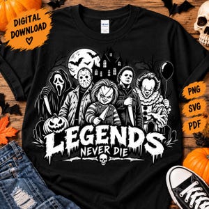 May include: A black t-shirt featuring a graphic print of five horror movie characters, a haunted house, bats, and a full moon. The text "LEGENDS NEVER DIE" is printed in a white, dripping font above a small skull icon at the bottom of the design.