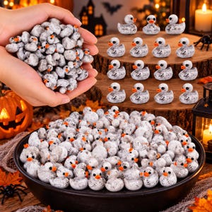 Könnte beinhalten: Eine große Sammlung von Miniatur-Gummienten mit einem abgenutzten weiß-grauen Finish, leuchtend orangefarbenen Schnäbeln und schwarzen Augen. Die Enten sind in einer schwarzen Schale, in einer Hand und auf einem hölzernen Etagenständer arrangiert.