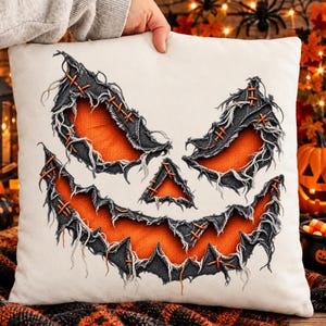 Peut inclure: Un coussin carré blanc cassé orné d'un motif de visage de citrouille d'Halloween. Le design se compose de pièces de tissu gris foncé effilochées, cousues avec du fil orange sur un fond orange vif, formant deux yeux, un nez et une bouche.