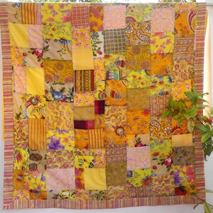 Peut inclure: Une courtepointe patchwork jaune, orange et rose avec une vari&eacute;t&eacute; de motifs floraux et paisley.