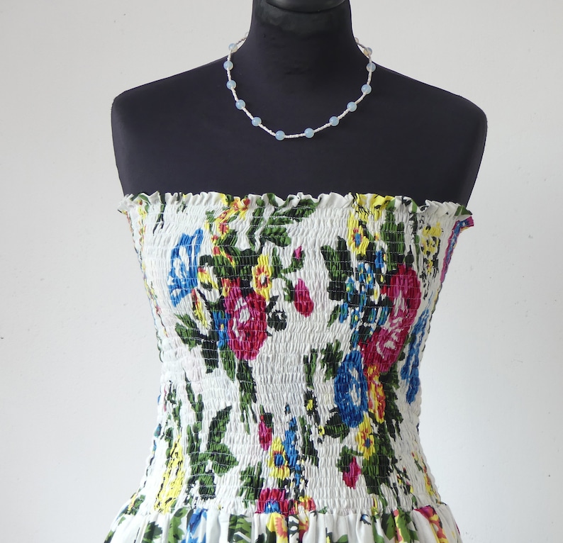 Mid-length strapless dress with smocked bodice on a 35-panel skirt in white cotton flower print with matching scarf