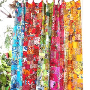 Peut inclure: Rideaux patchwork colorés avec divers motifs et couleurs, dont le bleu, le rouge, le vert, le rose et le jaune. Les rideaux sont faits de carrés de tissu cousus ensemble, créant un design vibrant et éclectique. Les rideaux sont suspendus, probablement pour une fenêtre ou une porte.