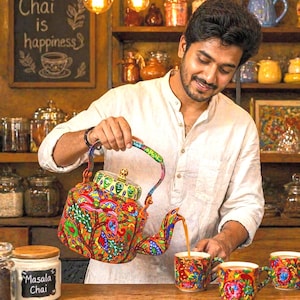 May include: A colorful, patterned teapot pouring tea into matching mugs. The teapot and mugs feature a vibrant design with red, orange, blue, and green hues. The image includes a chalkboard sign that reads "Chai is happiness."