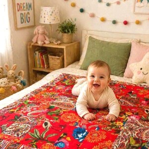 Peut inclure: Une courtepointe en patchwork rouge vif présentant un mélange de motifs floraux, cachemire et botaniques dans des tons de bleu, orange et vert. La courtepointe est rectangulaire avec une bordure cousue et est étalée sur une surface de lit.