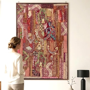 Könnte beinhalten: Ein großer, rechteckiger Wandteppich mit Patchwork-Design. Der Wandteppich weist eine Vielzahl von Farben auf, darunter Rot, Burgunder, Gold und Grün. Das Design umfasst florale und geometrische Muster. Der Wandteppich ist in dunklem Holz gerahmt.
