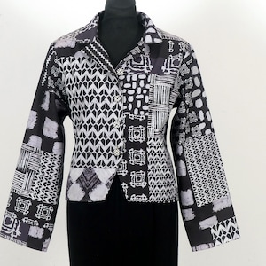 Peut inclure: Une veste boutonnée à manches longues avec un motif noir et blanc. La veste présente un design patchwork avec des formes géométriques et des motifs abstraits.