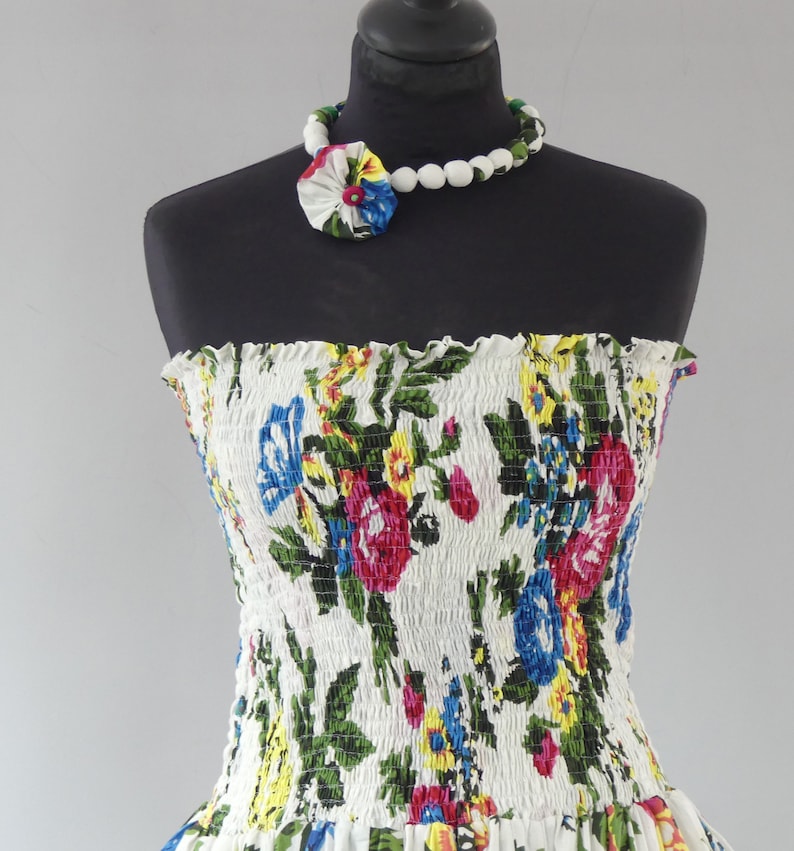Mid-length strapless dress with smocked bodice on a 35-panel skirt in white cotton flower print with matching scarf