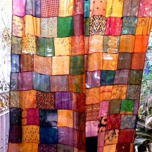 May include: A colorful patchwork curtain made of various fabrics with different patterns and textures. The curtain is made up of squares of different colors, including red, orange, yellow, green, blue, purple, and brown.