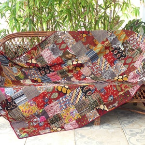 Peut inclure: Une courtepointe patchwork avec une vari&eacute;t&eacute; de couleurs et de motifs, drap&eacute; sur un canap&eacute; en osier. La courtepointe est faite de diff&eacute;rents tissus, y compris des imprim&eacute;s floraux, des motifs paisley et des motifs g&eacute;om&eacute;triques.