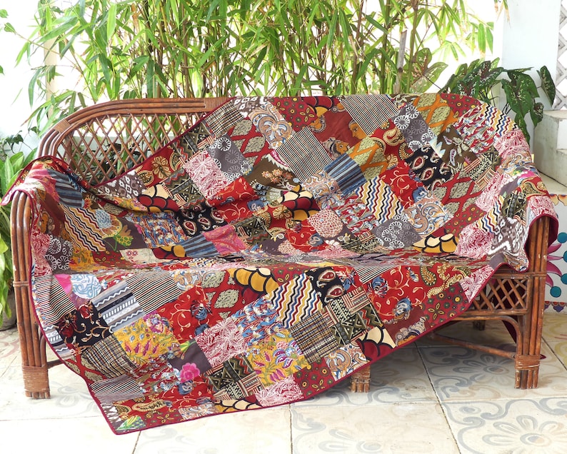 Peut inclure: Une courtepointe patchwork avec une vari&eacute;t&eacute; de couleurs et de motifs, drap&eacute; sur un canap&eacute; en osier. La courtepointe est faite de diff&eacute;rents tissus, y compris des imprim&eacute;s floraux, des motifs paisley et des motifs g&eacute;om&eacute;triques.