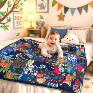 Peut inclure: Un bébé souriant est allongé sur une courtepointe patchwork à bordure bleu marine. La courtepointe présente divers motifs floraux et géométriques colorés. La chambre d'enfant est décorée d'une fresque d'arbre, d'art encadré et d'un oreiller en forme de nuage.