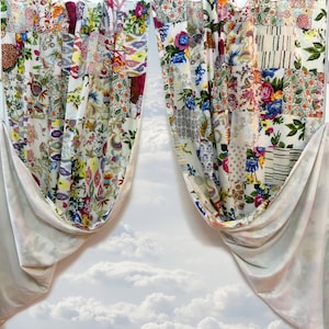 May include: Two white curtains with a patchwork design featuring floral patterns in shades of pink, red, blue, and green. The curtains are tied back and the background is a cloudy sky.
