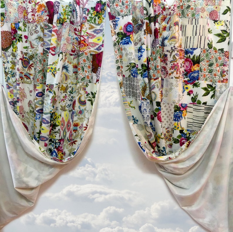 May include: Two white curtains with a patchwork design featuring floral patterns in shades of pink, red, blue, and green. The curtains are tied back and the background is a cloudy sky.
