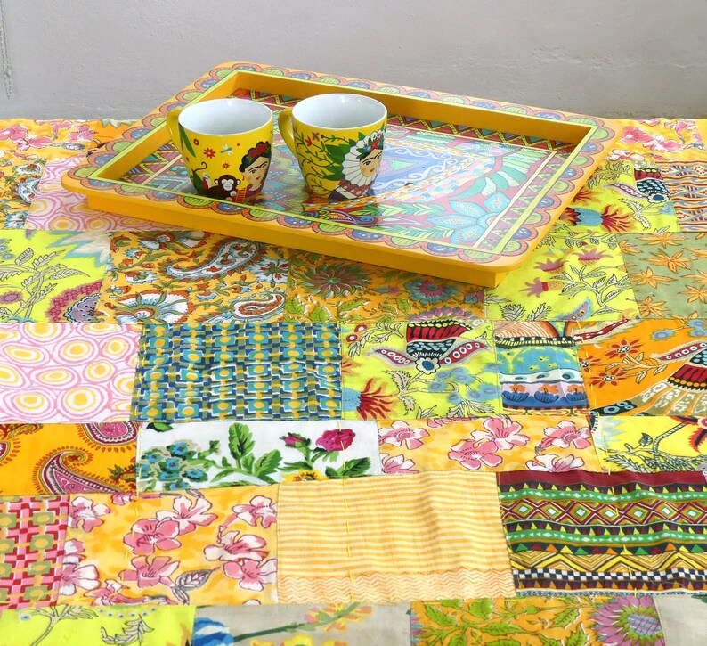 Peut inclure: Un plateau jaune avec un motif floral color&eacute; et un bord festonn&eacute;. Deux tasses en c&eacute;ramique jaunes avec des motifs color&eacute;s sont sur le plateau. Le plateau est sur une courtepointe en patchwork avec une vari&eacute;t&eacute; de tissus color&eacute;s.