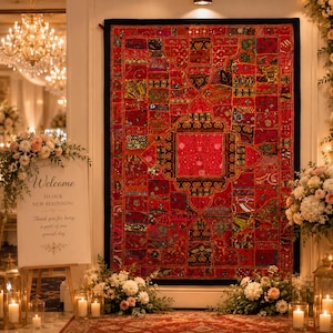 May include: A large rectangular wall hanging featuring a vibrant red patchwork design with intricate gold embroidery, sequins, and beadwork. The textile displays a central square motif surrounded by smaller geometric panels with black borders.