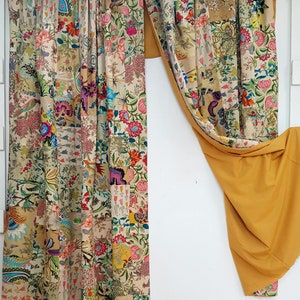 May include: A pair of curtains with a patchwork design featuring a variety of floral patterns in shades of pink, blue, green, and yellow. The curtains are made of a lightweight fabric and have a subtle sheen. The curtains are hung on a white rod and are pulled back to reveal a yellow fabric behind them.