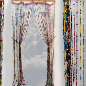 May include: A colorful beaded curtain made of fabric scraps and wooden beads. The curtain is hung in a window and lets in natural light.