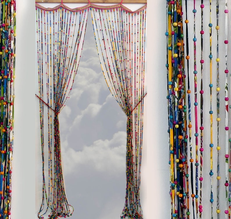 May include: A colorful beaded curtain made of fabric scraps and wooden beads. The curtain is hung in a window and lets in natural light.