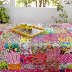 K&ouml;nnte beinhalten: Eine bunte Patchwork-Tischdecke mit einem gelben Tablett und zwei wei&szlig;en Keramikbechern mit Blumendesigns. Die Tischdecke besteht aus verschiedenen Stoffen in verschiedenen Farben und Mustern.