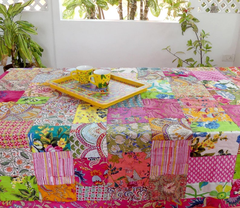 K&ouml;nnte beinhalten: Eine bunte Patchwork-Tischdecke mit einem gelben Tablett und zwei wei&szlig;en Keramikbechern mit Blumendesigns. Die Tischdecke besteht aus verschiedenen Stoffen in verschiedenen Farben und Mustern.