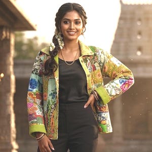 May include: A vibrant, patterned quilted jacket with a floral design. The jacket features a lime green trim and is worn over a black top and trousers. The design incorporates shades of blue, red, yellow, and green.