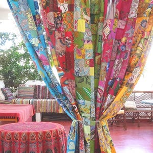 Könnte beinhalten: Ein bodenlanger Vorhang, der aus zahlreichen kleinen, rechteckigen Stoffstücken in einem Patchwork-Design zusammengenäht ist. Der Stoff weist eine Vielzahl lebendiger Farben auf, darunter Rot, Gelb, Grün, Blau und Pink, mit verschiedenen Blumen- und geometrischen Mustern.