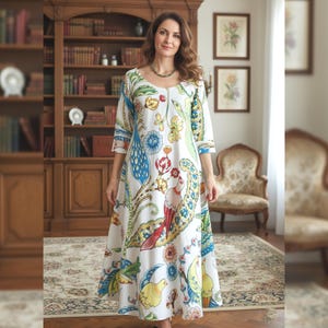 Peut inclure: Une robe longue blanche ornée d'un motif floral et cachemire coloré. La robe présente un col rond et des manches trois-quarts. Le motif comprend des éléments bleus, jaunes, rouges et verts.