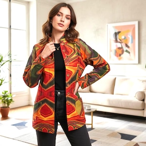 Peut inclure: Veste boutonnée vibrante avec un motif abstrait coloré dans les tons de rouge, orange, jaune et vert. La veste a un col mandarin et deux poches avant. Le modèle porte un haut noir et un jean foncé.