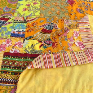 Peut inclure: Une courtepointe patchwork avec une vari&eacute;t&eacute; de motifs floraux et g&eacute;om&eacute;triques color&eacute;s. La courtepointe est faite de diff&eacute;rents tissus cousus ensemble dans un motif al&eacute;atoire. La courtepointe est jaune, orange, rouge, vert, bleu et rose.