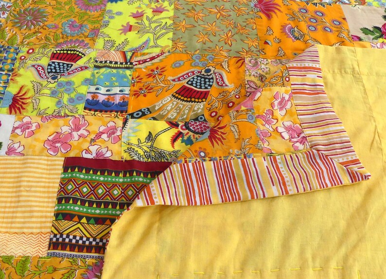 Peut inclure: Une courtepointe patchwork avec une vari&eacute;t&eacute; de motifs floraux et g&eacute;om&eacute;triques color&eacute;s. La courtepointe est faite de diff&eacute;rents tissus cousus ensemble dans un motif al&eacute;atoire. La courtepointe est jaune, orange, rouge, vert, bleu et rose.