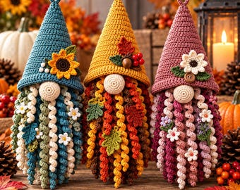 May include: Three handmade crochet gnomes with tall pointed hats. The left gnome has a blue hat with a sunflower, the center has a yellow hat with leaves and berries, and the right has a mauve hat with a white flower and wooden button.