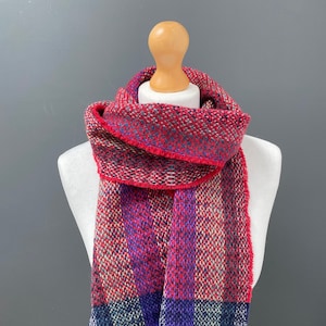 May include: A red, purple, and blue plaid scarf with a fringed edge.