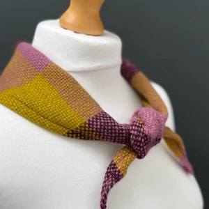 pink, yellow and burgundy triangle neckerchief tie on a mannequin against a dark grey background
